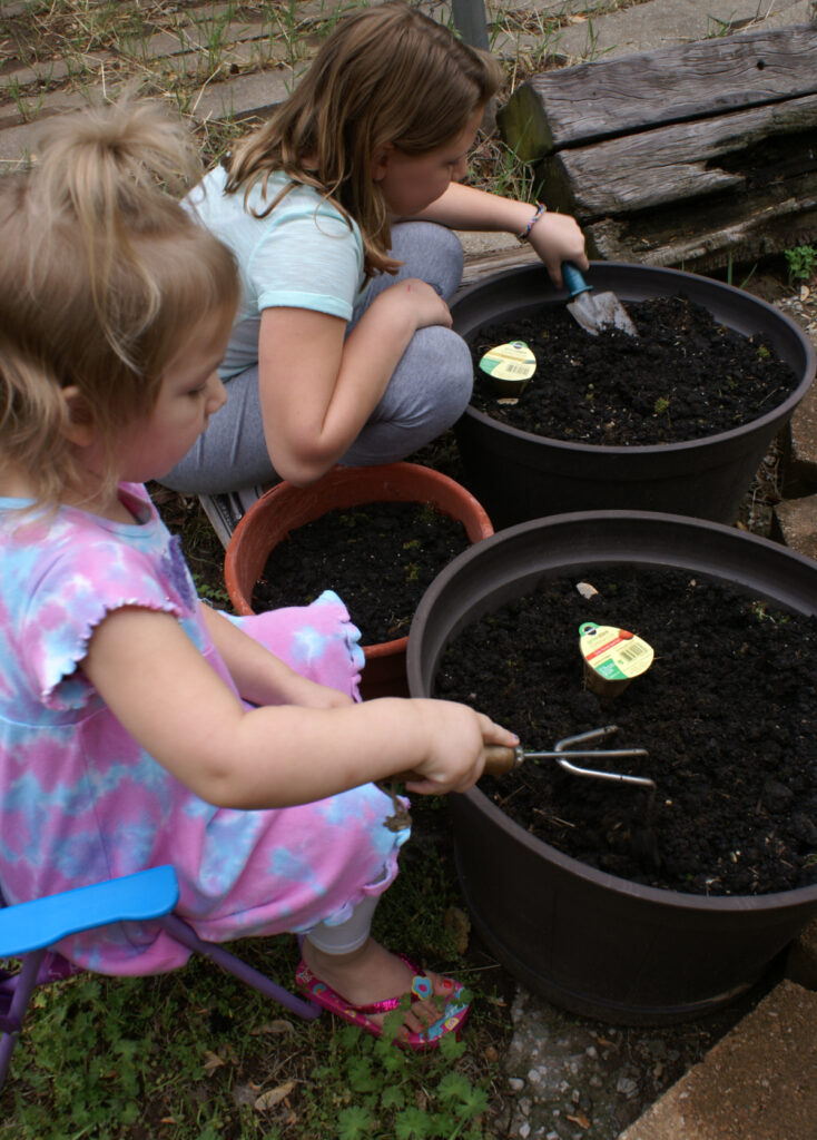 two girls planting in small outdoor planters