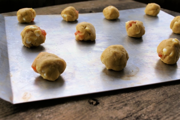 balls of cookie dough for orange cookies on a baking sheet uncooked