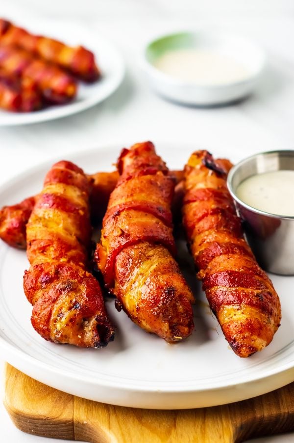 white plate holding 3 bacon wrapped chicken tenders