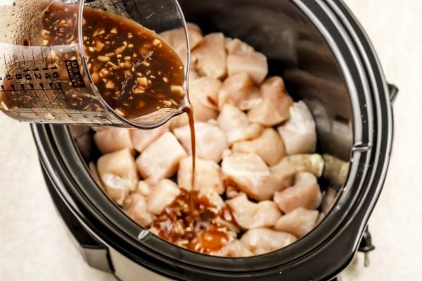 pouring sauce on Weight Watchers Bourbon Chicken in the Crockpot