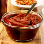 glass bowl of sugar-free BBQ sauce with a spoon in the bowl