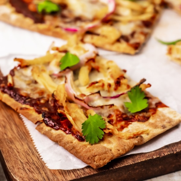 close up of Air Fryer BBQ chicken pizza slice on a wood cutting board