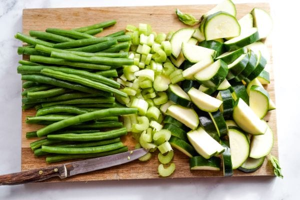 cutting board full of green beans, chopped celery and chopped zucchini