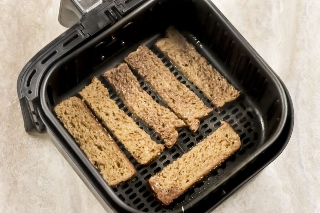 french toast sticks in air fryer basket getting ready to air fry