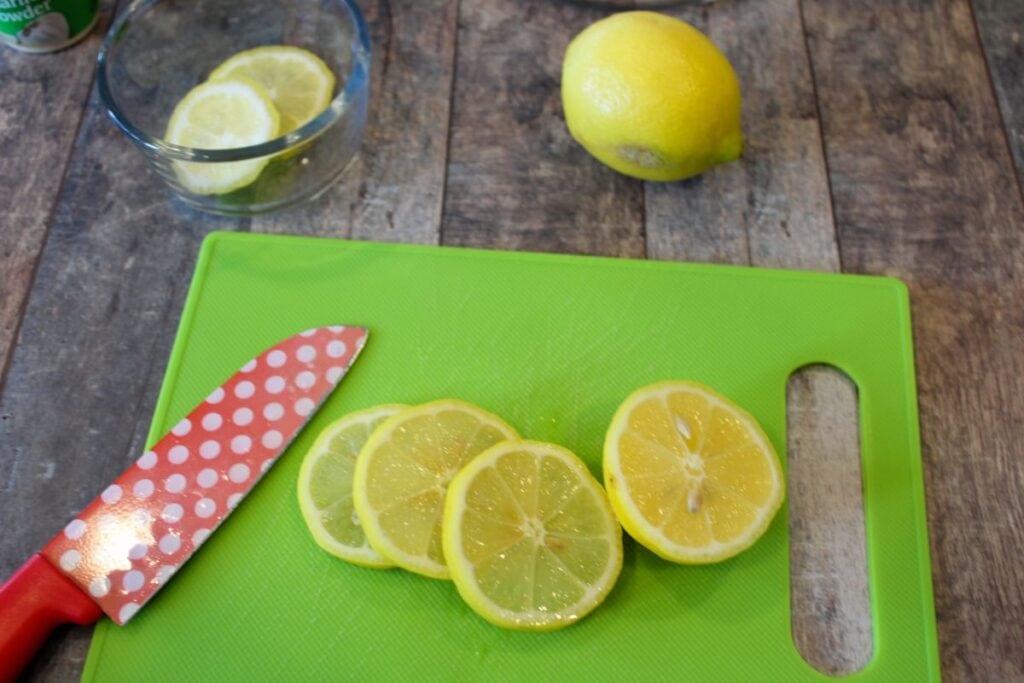 cutting board with sliced lemons and a red knife