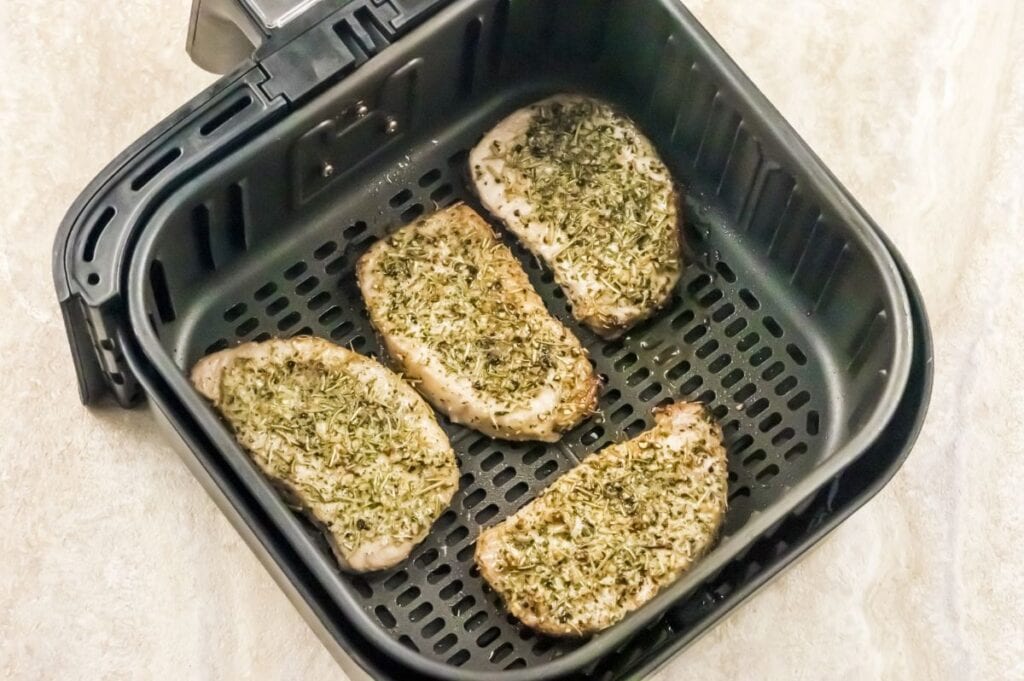 air fryer basket with cooked garlic and herb pork chops