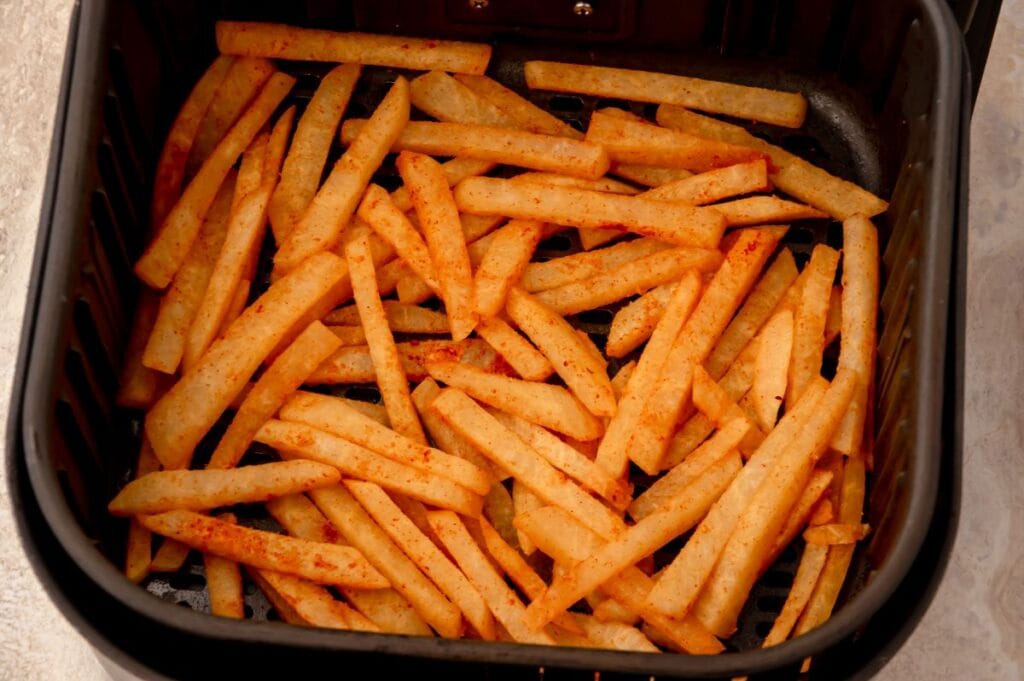 air fryer basket with jicama fries ready to cook