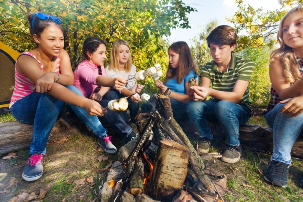 kids sitting around a bonfire roasting marshmallows