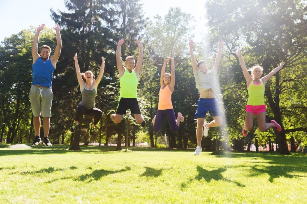 teens dressed in workout clothing jumping in the air