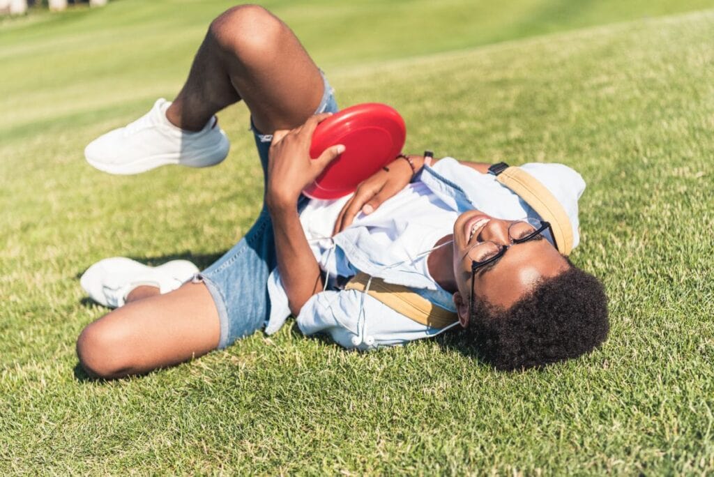 teen boy laying on the grass holding a frisbee
