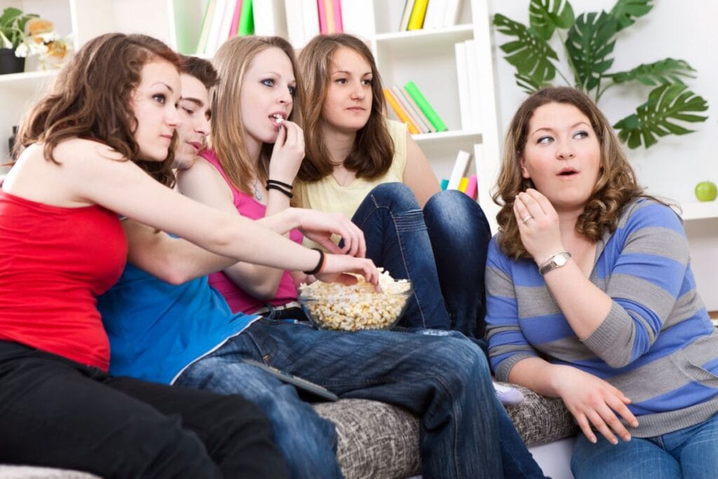 teens watching a movie eating popcorn at home