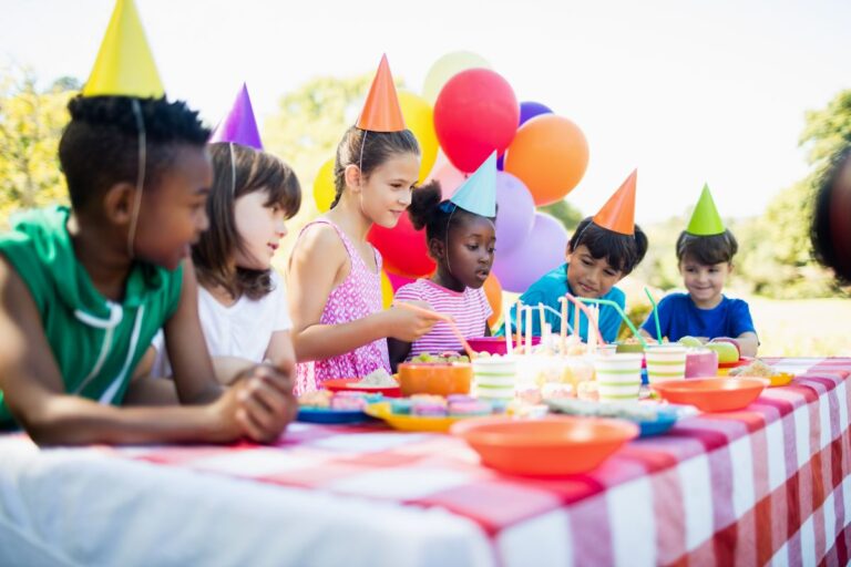 birthday party with a bunch of kids and a cake and balloons