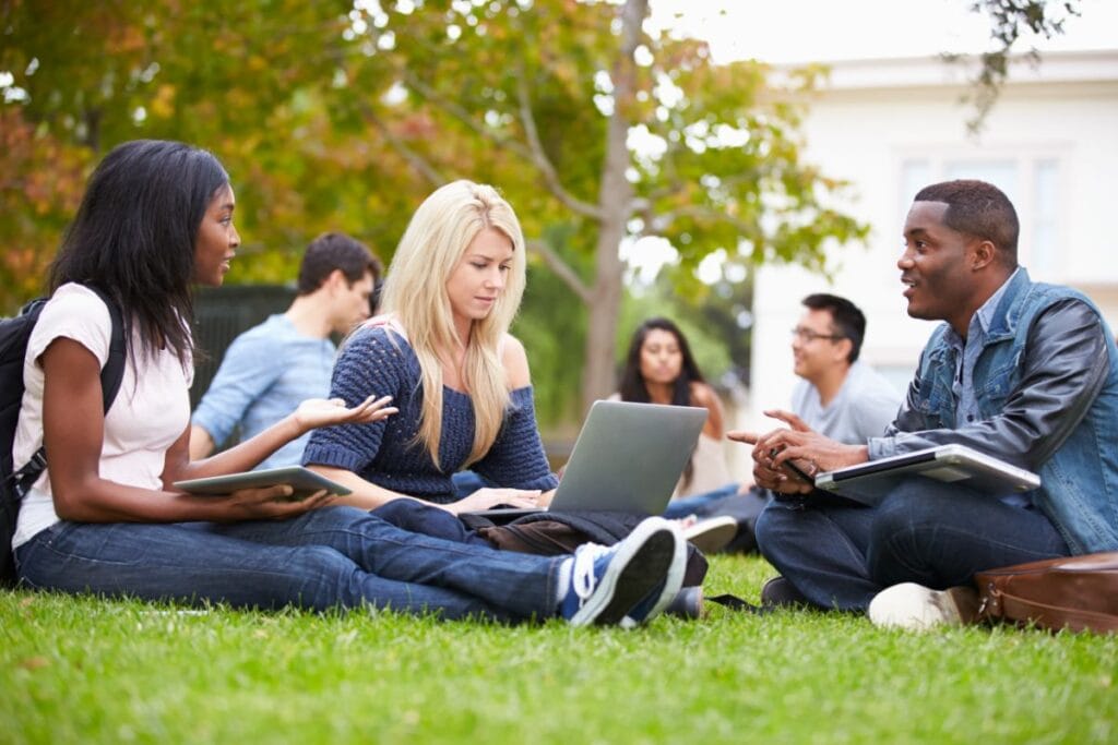 college students talking and sitting on grass