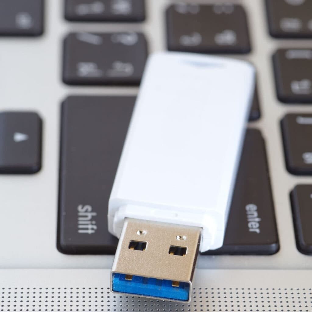 white flash drive on top of a laptop