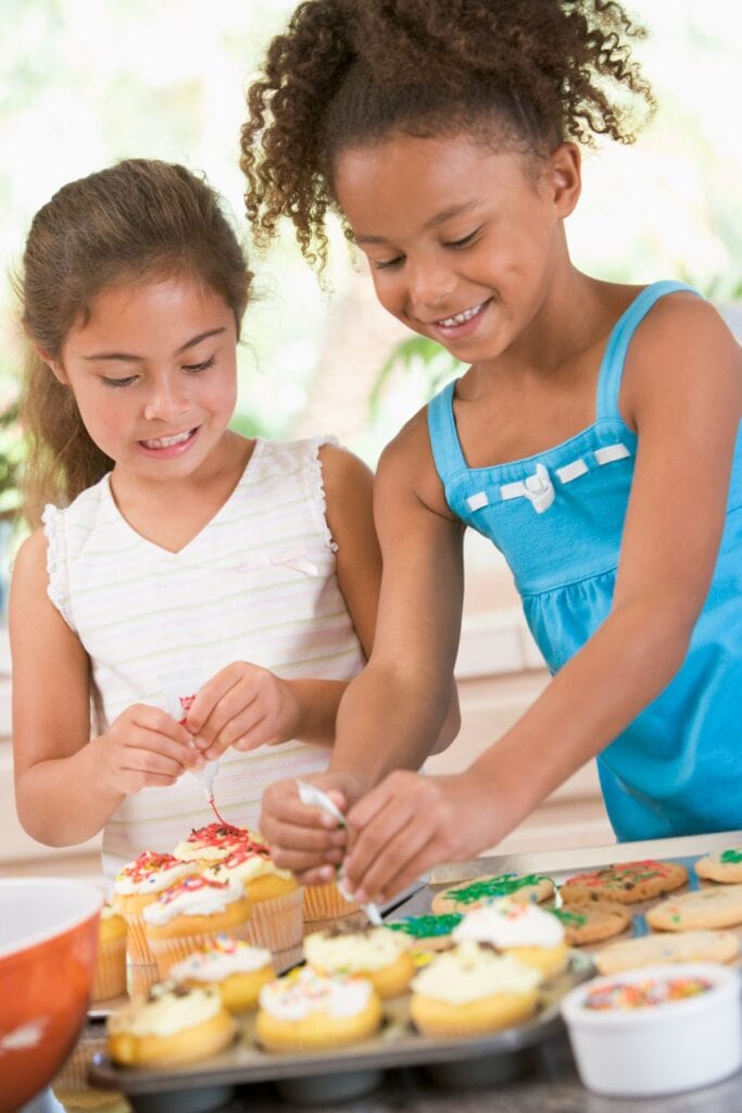 2 girls decorating cupcakes