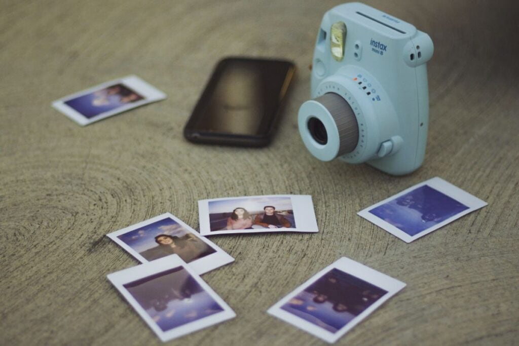 instant camera with small photos laying around it