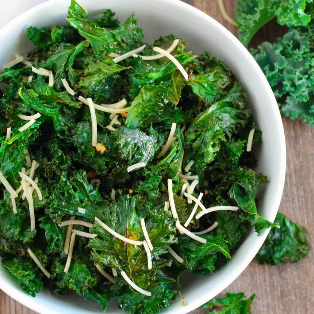 bowl of kale chips with shredded parmesan cheese on top