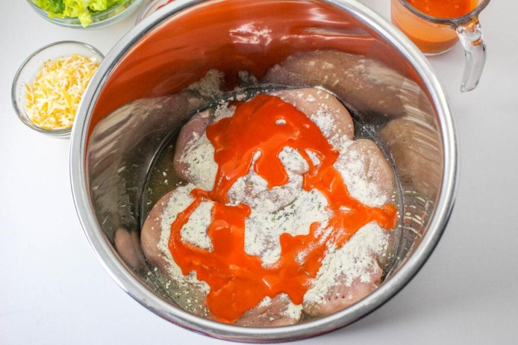 chicken breasts with seasoning and buffalo sauce