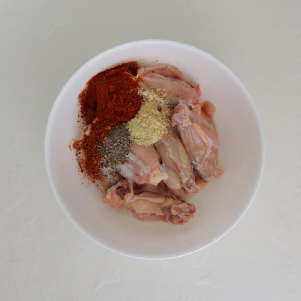 bowl of raw wings with seasoning