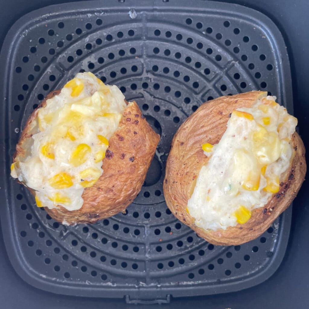 2 baked potatoes in an air fryer basket