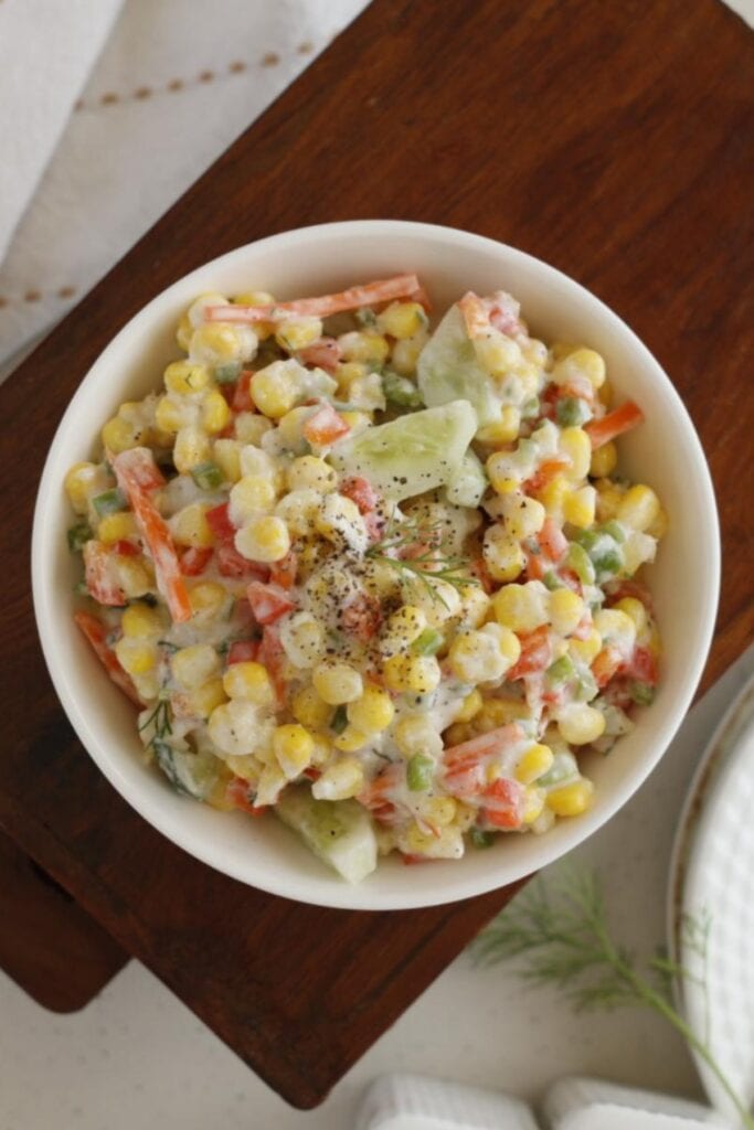 bowl of corn & cucumber salad on a chopping board