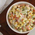 close up view of a bowl of salad with cucumber, corn, and carrots