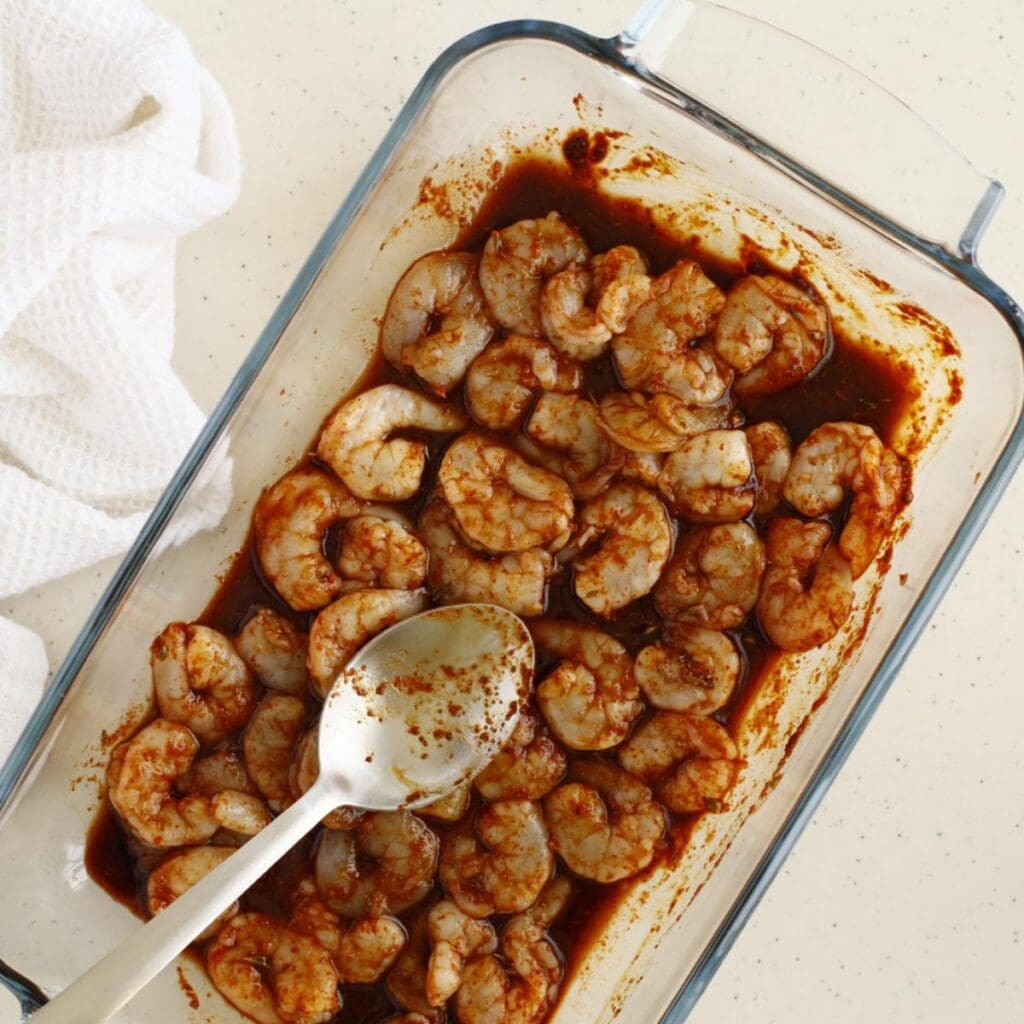 raw shrimps in a baking pan with cajun mixture