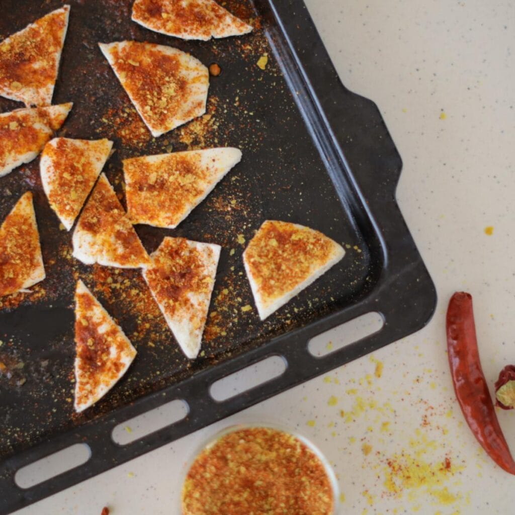 tortilla chips with spices on a baking pan