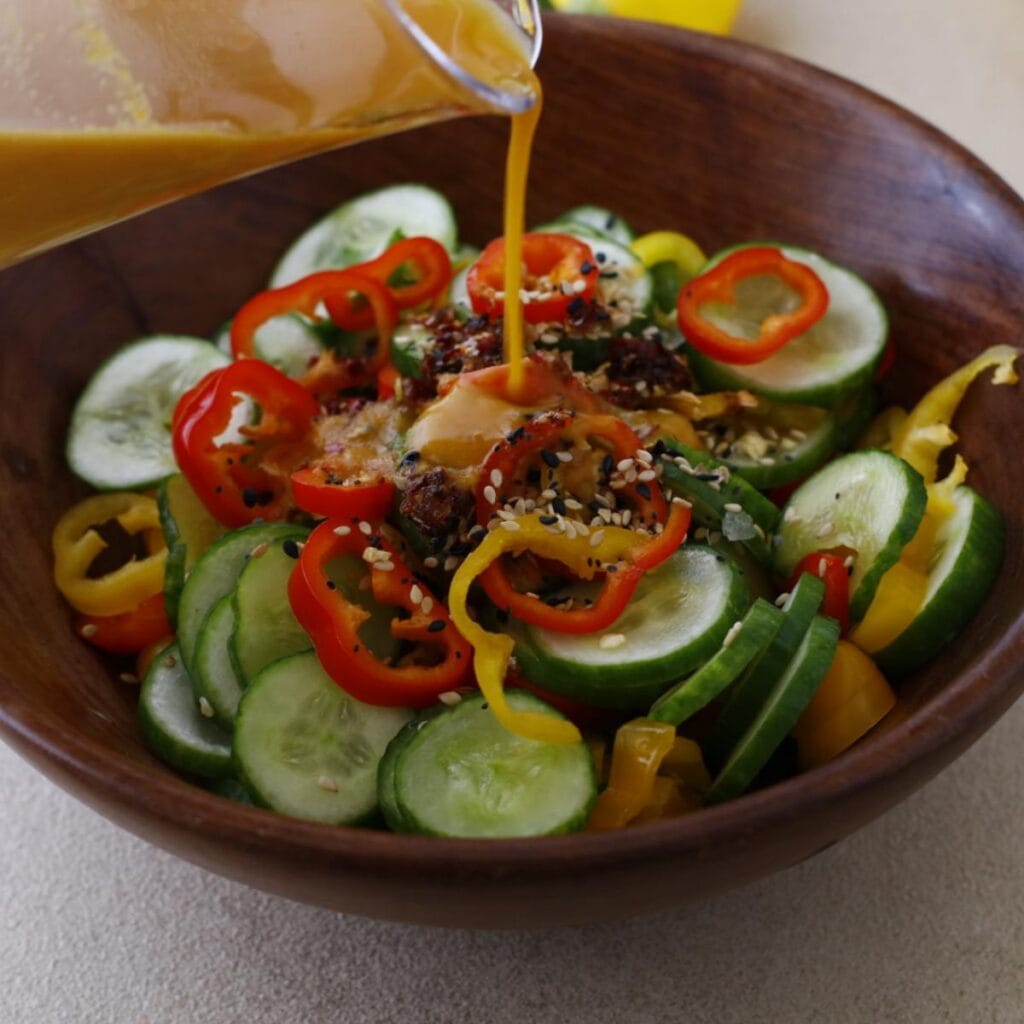 pouring sesame dressing into a salad bowl