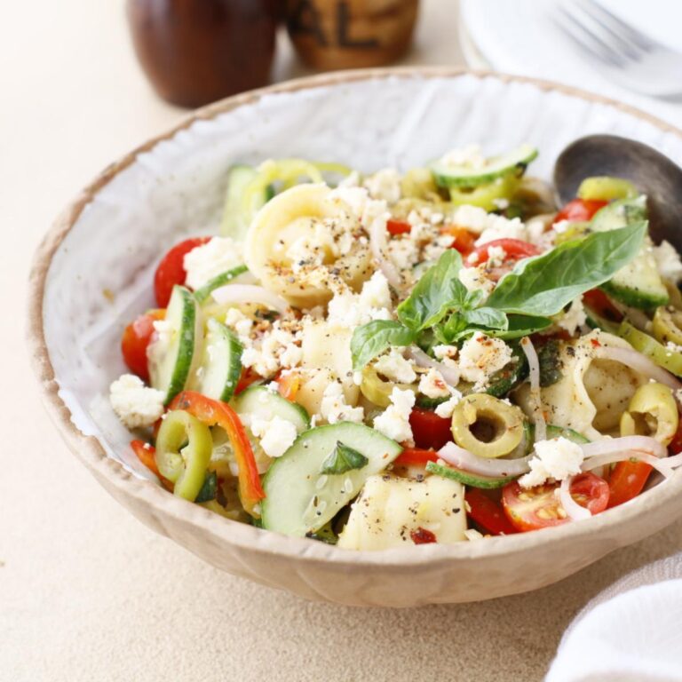 pasta salad topped with basil and feta cheese