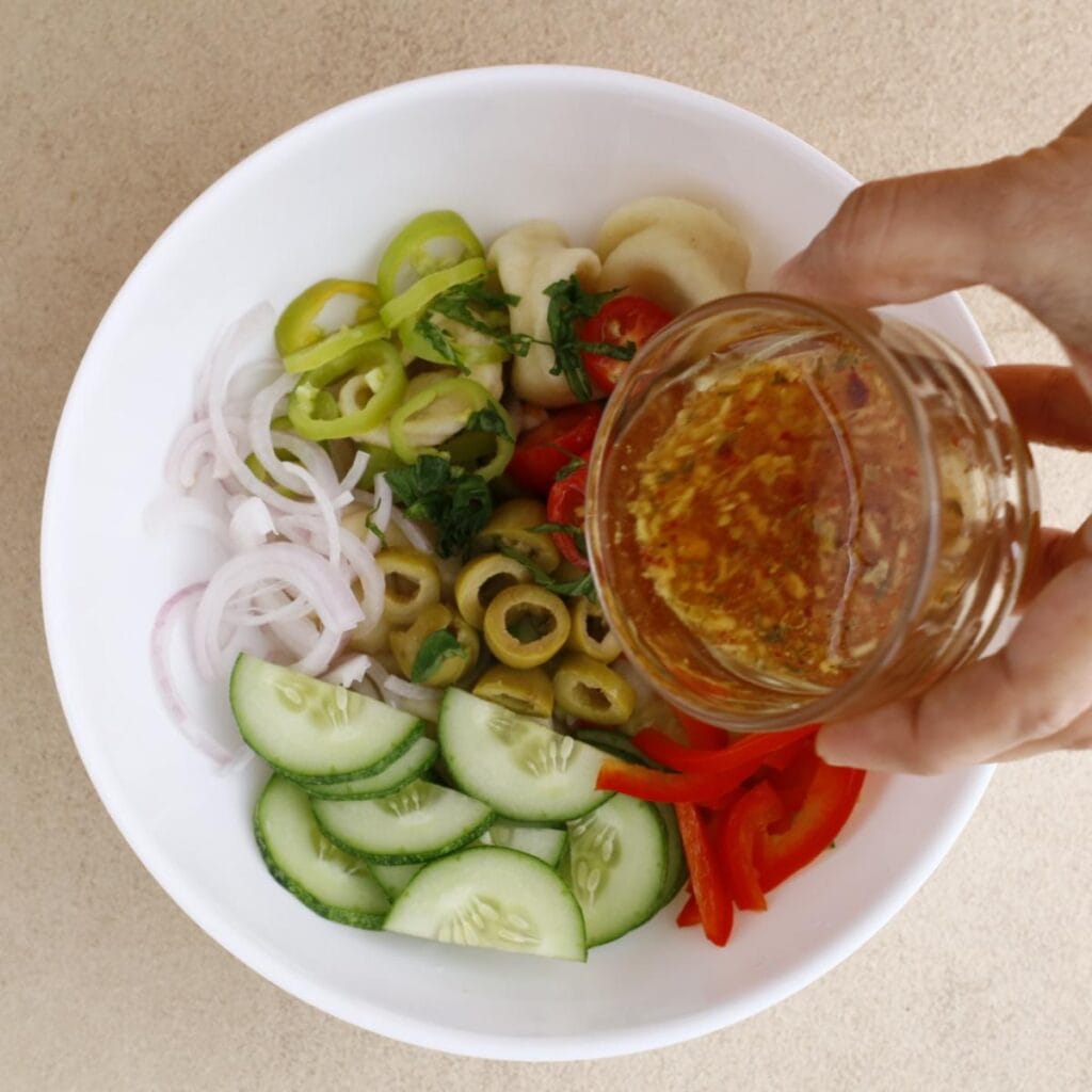pouring dressing on pasta salad