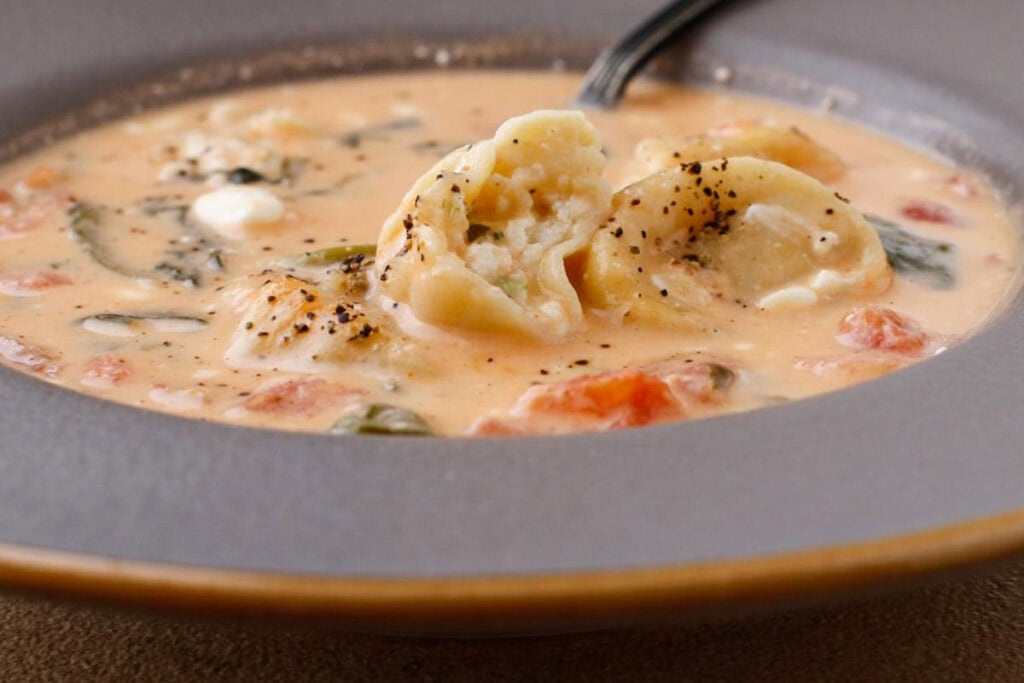 close up view of soup and the inside of a tortellini