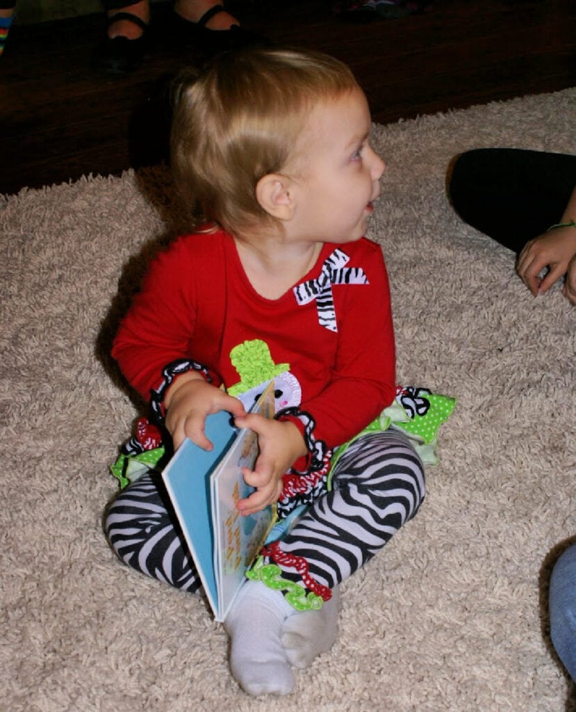 baby sitting holding a book