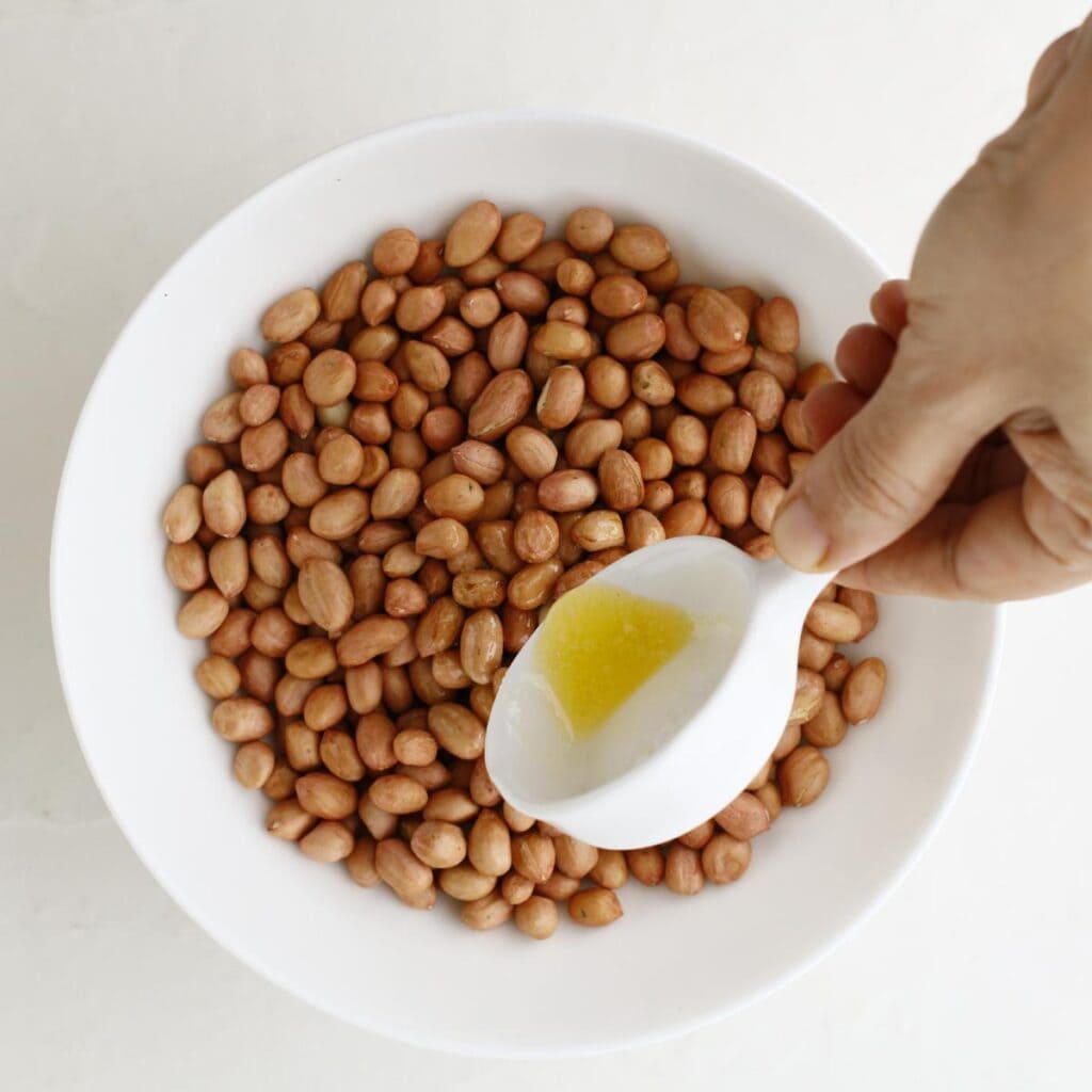 pouring butter over a bowl of peanuts