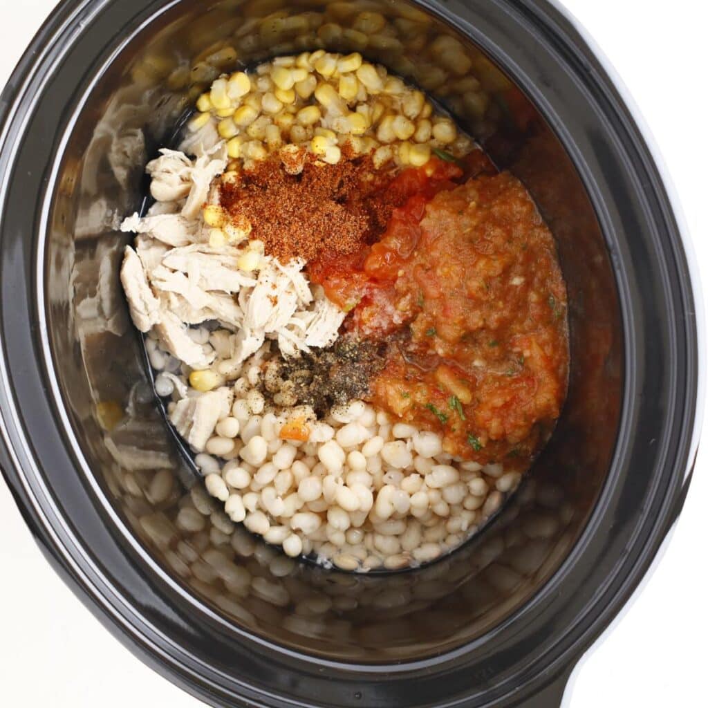 slow cooker pot filled with beans, chicken, corn, and salsa