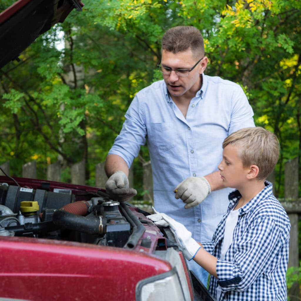 dad and son learning to change the oil in the car