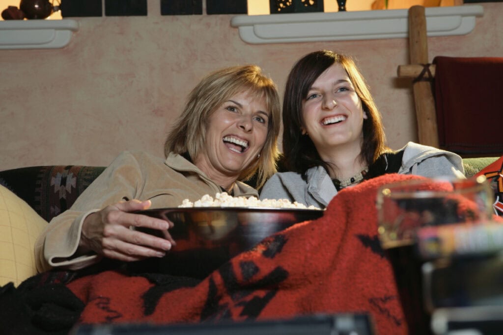 two women watching a movie with popcorn