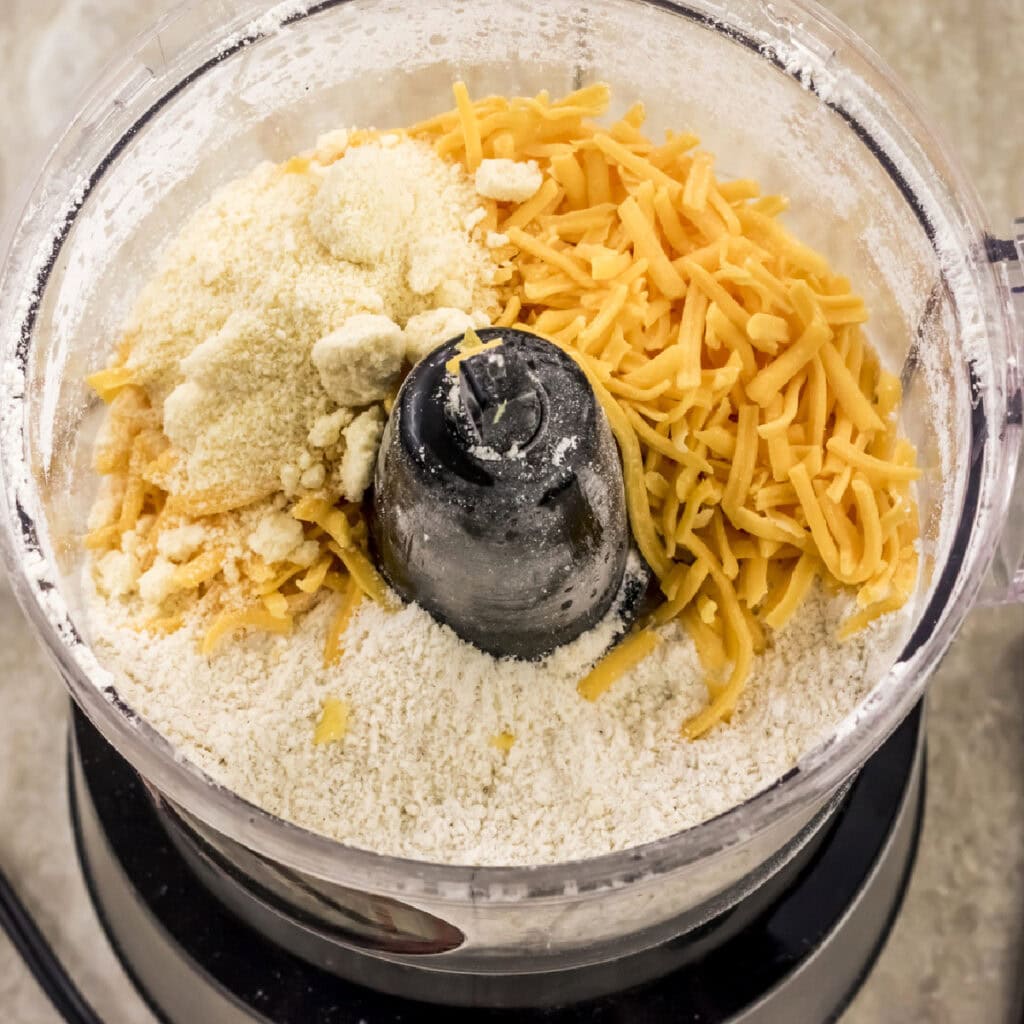 adding mixture to the blender for making cheese straws