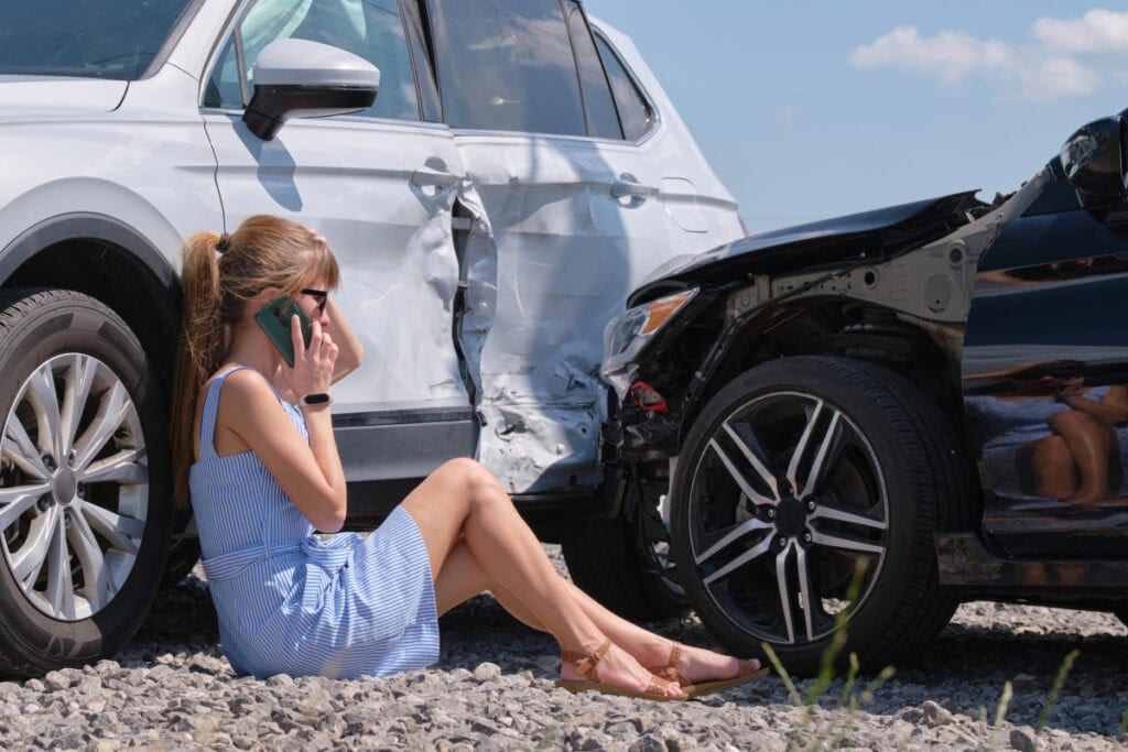 woman sitting by a car that was in an accident