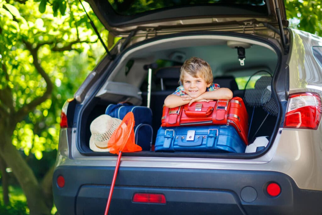 boy in back of vehicle with suit cases
