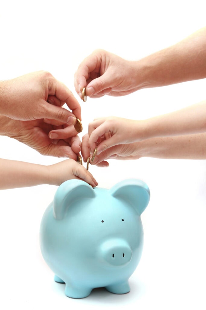 hands putting money into a piggy bank