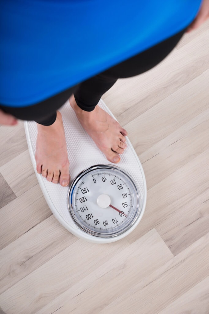 woman standing on scale on a weight loss journey