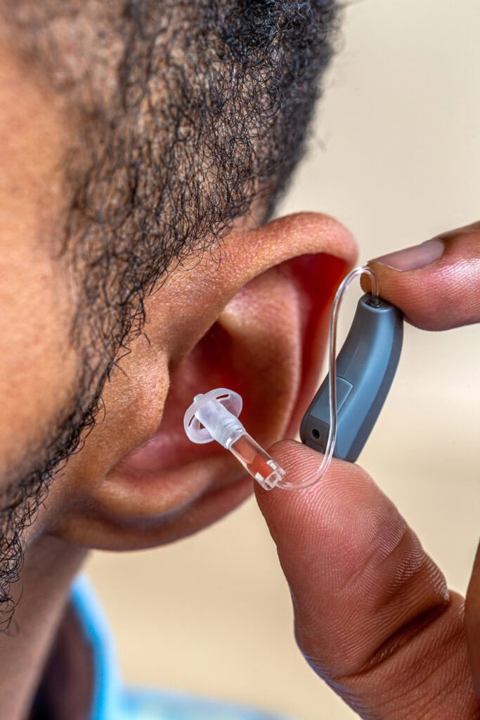 man putting hearing aid in