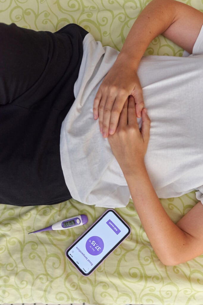 woman using a fertility app in bed
